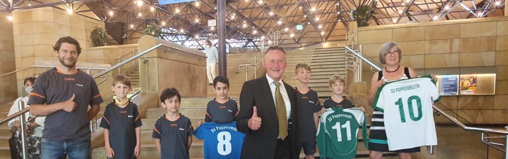 Das Bild zeigt mehrere Erwachsene und Kinder die T-Shirts vom SV Poppenreuth hochhaltem
