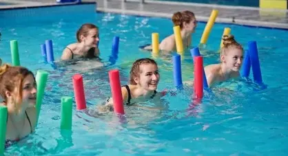 Das Bild zeigt Kinder im Schwimmbad mit Poolnudeln