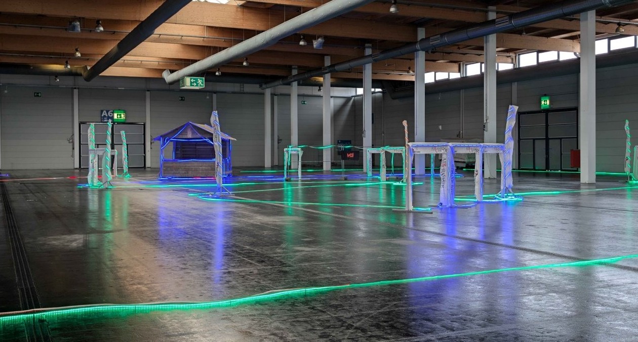 Im Bild sind Gates mit LED Beleuchtung in einer Messehalle mit dunklem Boden zu sehen.